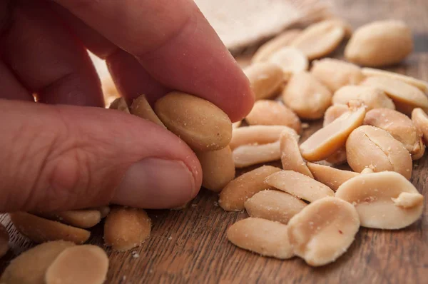 Gros Plan Cacahuètes Salées Dans Les Doigts Sur Fond Bois — Photo