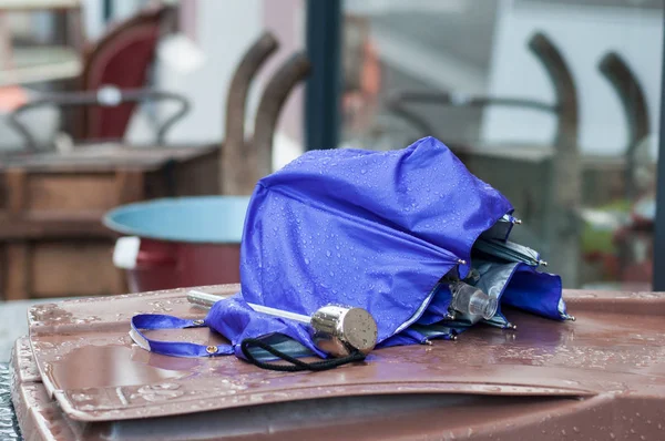 closeup of broken umbrella abandoned on a trash can in the street