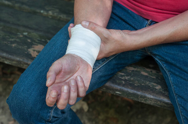 Крупный план человека с растяжением запястья сидя на открытом воздухе

