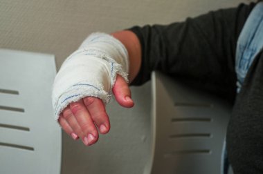 Kadın el el cerrahi bekleme odasında oturuyor, sonra kol bandaj ile closeup