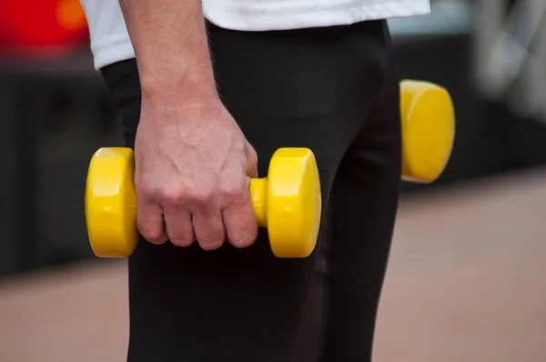 closeup of man with yellow dumbbells in hands