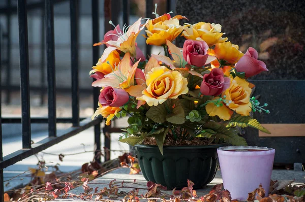 closeup of artificial flowers on tomb in cemetery