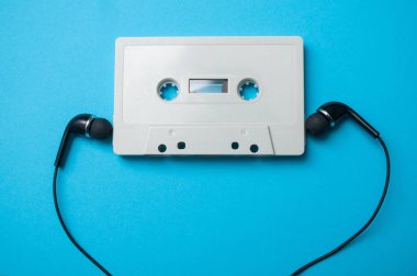 mavi arka plan üzerinde siyah kulaklık ile vintage ses Kaset closeup 