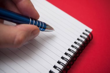 spirales not defterindeki kırmızı zemin üzerine mavi kalemle yazma adamın elini closeup