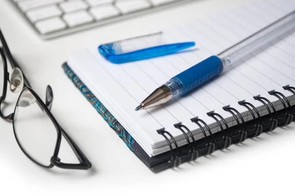 Närbild av blå penna på spirales anteckningsbok på vita skrivbord bakgrund — Stockfoto