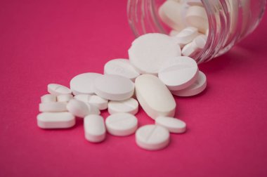 pembe arka plan cam kapsayıcıdan düşen beyaz pils closeup