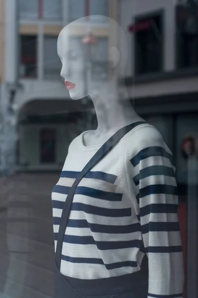 closeup of stripes navy blue pullover and winter coat on mannequin in fashion store showroom for women