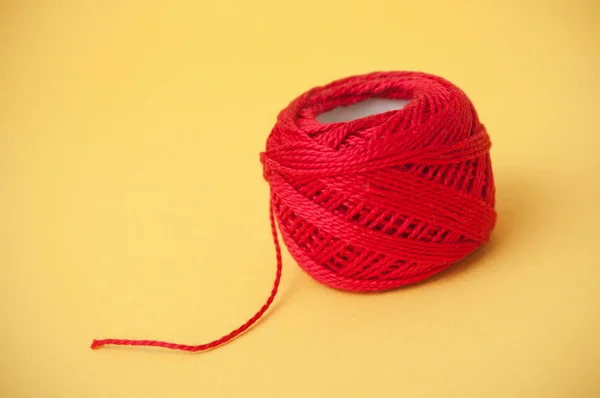 closeup of red string bobbin on yellow background