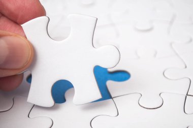 Parçalı bulmaca görevi tamamlamak için mavi arka plan üzerinde son parçası ile koyarak adam closeup el