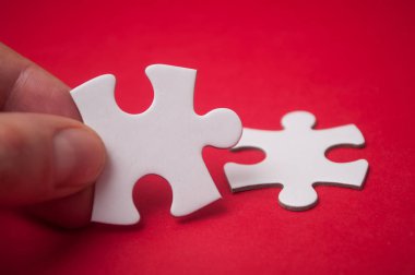 Adam iki parçalı bulmaca parça kırmızı zemin üzerine el ile bağlama closeup. Takım çalışması doğru çözümler bulma kavramı.