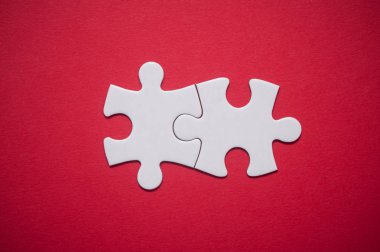 Kırmızı zemin üzerine iki bağlı jigsaw puzzle parçaları closeup. Takım çalışması doğru çözümler bulma kavramı.