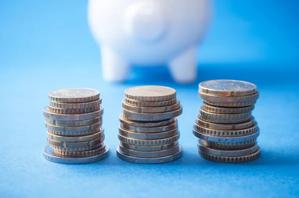 Closeup Euros Coins Piles Front White Piggy Bank Blue Background — Stock Photo, Image