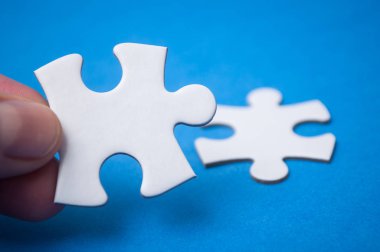 El ile mavi arka plan üzerinde iki parçalı bulmaca adet bağlayan adam closeup. Takım çalışması doğru çözümler bulma kavramı.