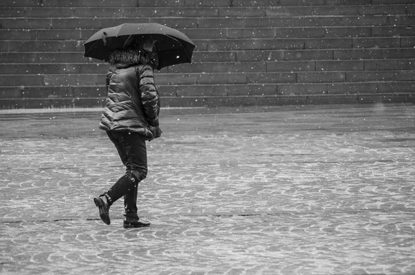 丸石の場所に雪の日に傘と冬のコートで歩いている女性の肖像画 — ストック写真