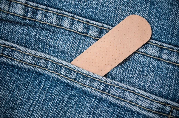 closeup of sticking plaster in blue jeans pocket