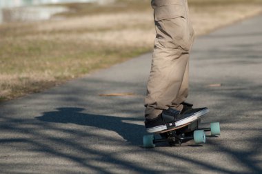closeup of legs of man on electric skate board on the road clipart