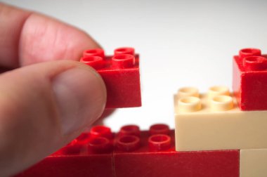 Beyaz arka plan üzerinde plastik tuğla inşaat ile oynarken adamın elini closeup