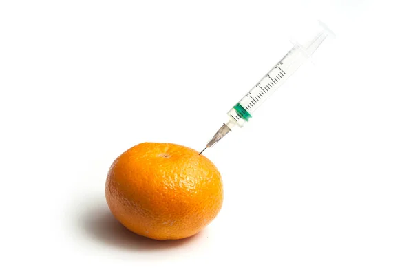 Closeup of injecting with a syringe into a tangerine on white ba — Stock Photo, Image