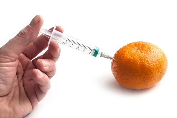 Closeup of hand of man injecting with a syringe into a tangerine — Stock Photo, Image