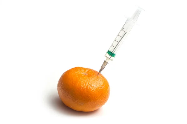 Closeup of injecting with a syringe into a tangerine on white ba — Stock Photo, Image