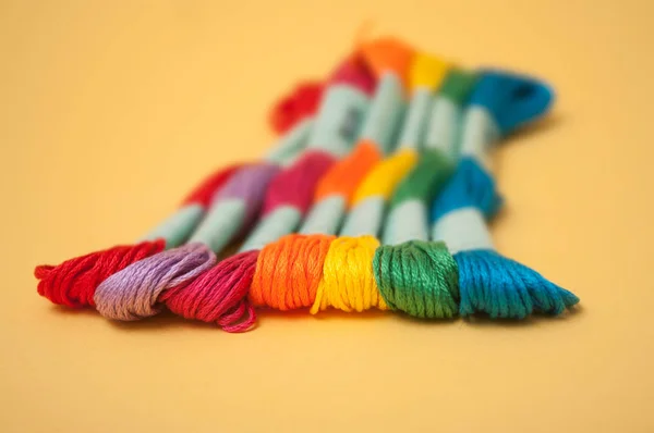 closeup of colorful cotton threads on yellow background