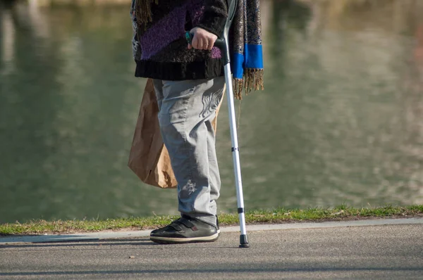 Close-up van leeftijd vrouw lopen met stok in stadspark — Stockfoto