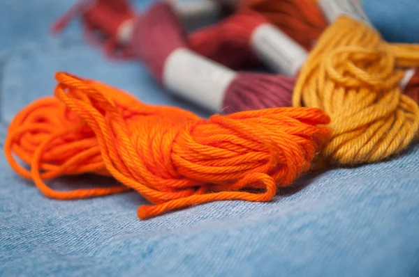 closeup of colorful cotton threads on blue jeans  background