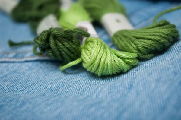Primer plano de hilos de algodón verde sobre fondo vaquero azul — Foto de Stock