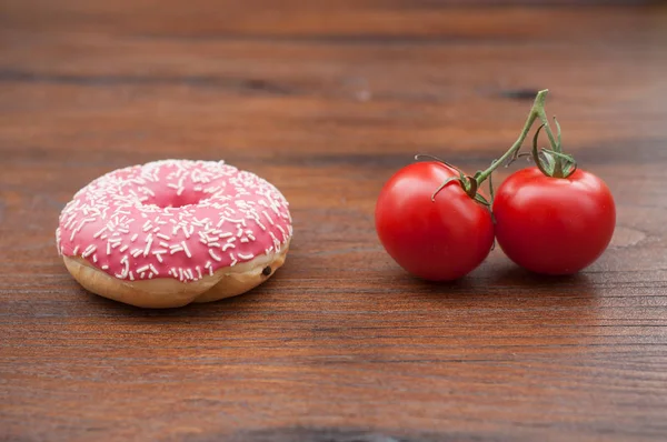 Rosado donut y tomates frescos en mesa de madera — Foto de Stock