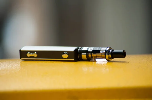 Closeup of grey electronic cigarette on yellow metallic background — Stock Photo, Image