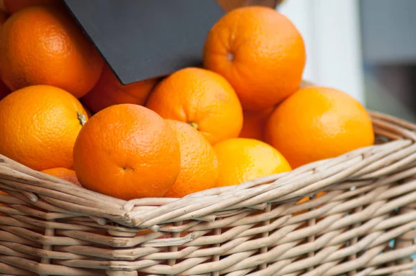 Closeup of organic oranges in a wooden basket at the market