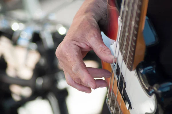 Close-up de mão do músico no baixo guitarra ao ar livre — Fotografia de Stock