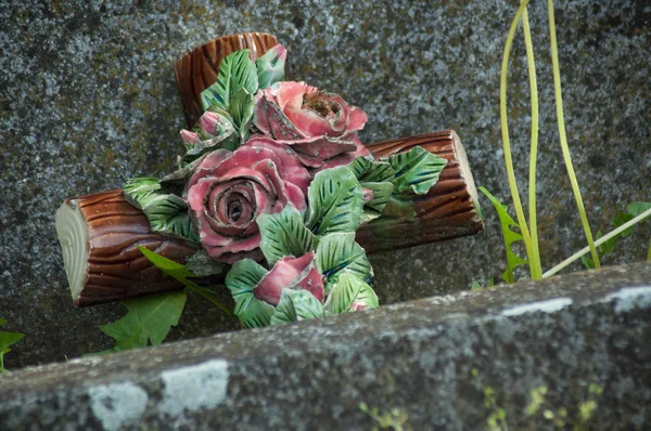 Närbild av keramiska korset i döda löv på grav på kyrkogården — Stockfoto