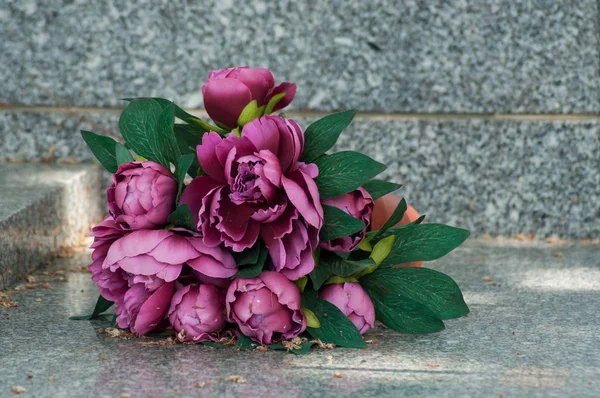 closeup of artificial flowers on tomb in cemetery