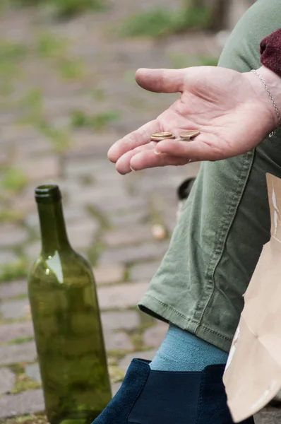 Moedas de euros na mão de mulher pobre sentada na rua — Fotografia de Stock