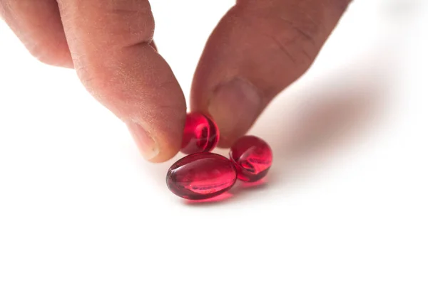 Gros plan de pilules rouges à la main sur fond blanc — Photo