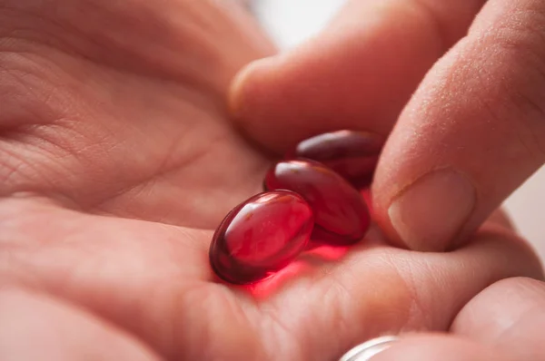 Gros plan de pilules rouges à la main sur fond blanc — Photo