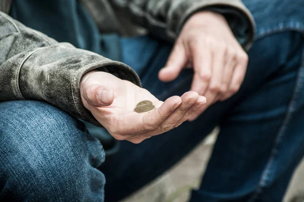 Closeup of euros coins in hand of poor man sitting in the street — Stock Photo, Image