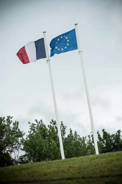 Primo piano delle bandiere francesi ed europee che galleggiano sul cielo grigio — Foto Stock