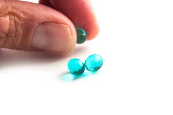 Close-up van blauwe pillen in de hand op witte achtergrond — Stockfoto