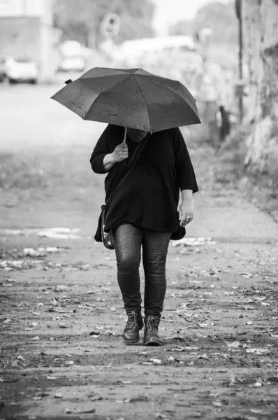 Portret van vrouw wandelen in de straat met een zwarte paraplu — Stockfoto