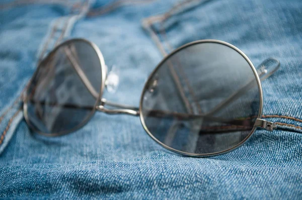 Closeup of sun glasses on blue jeans background — Stock Photo, Image