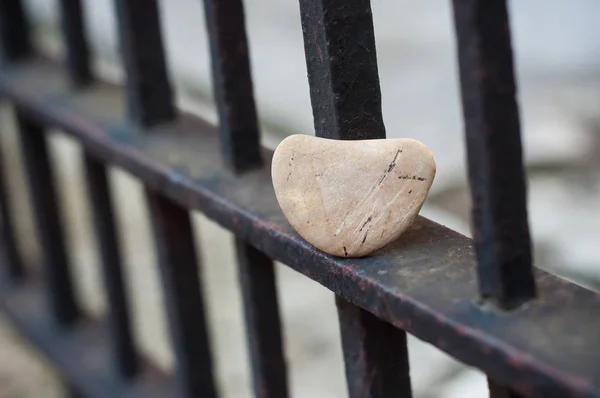 Zaostřená kamenného oblázek ve tvaru srdce na kovové mřížce — Stock fotografie