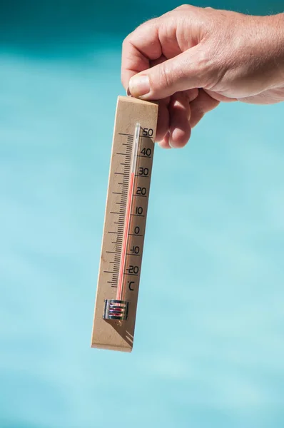 Nahaufnahme eines hölzernen Thermometers in der Hand im Grenzschwimmbecken — Stockfoto