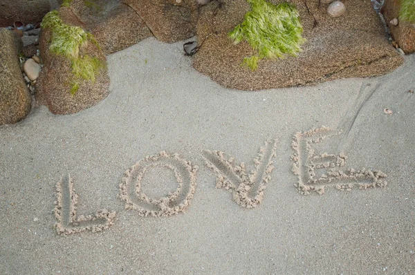 Close-up de escrita palavra de amor na areia na praia — Fotografia de Stock