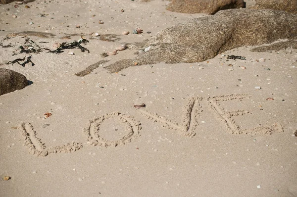 Close-up de escrita palavra de amor na areia na praia — Fotografia de Stock