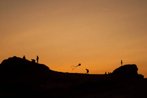 View of children silhouettes with kite flying on sunset landscape — Stock Photo, Image