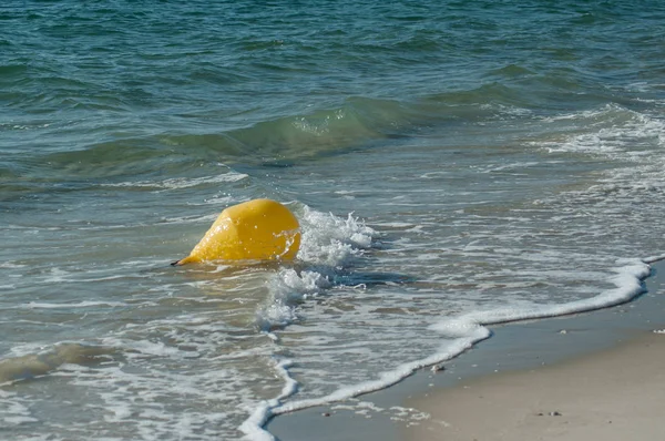 Zbliżenie żółtej boi w wodzie z oina na plaży — Zdjęcie stockowe