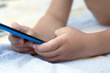 Elle akıllı telefon ile banyo havlusu yatıyor çocuk closeup