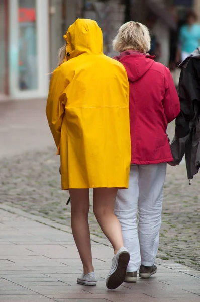 Giovane ragazza che cammina nella stree indossando cappotto giallo pioggia — Foto Stock